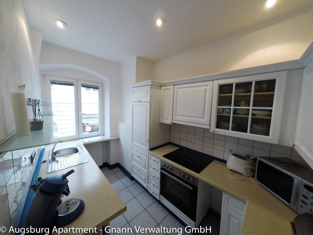 Küche mit Kochfeld, Backofen und Mikrowelle in einem möblierten Apartment in Augsburg