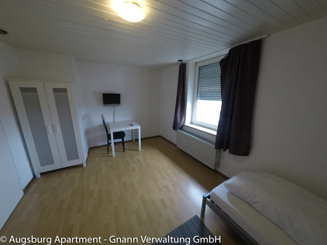 Einzelzimmer mit Kleiderschrank, Schreibtisch und TV in einer Monteurwohnung in Augsburg