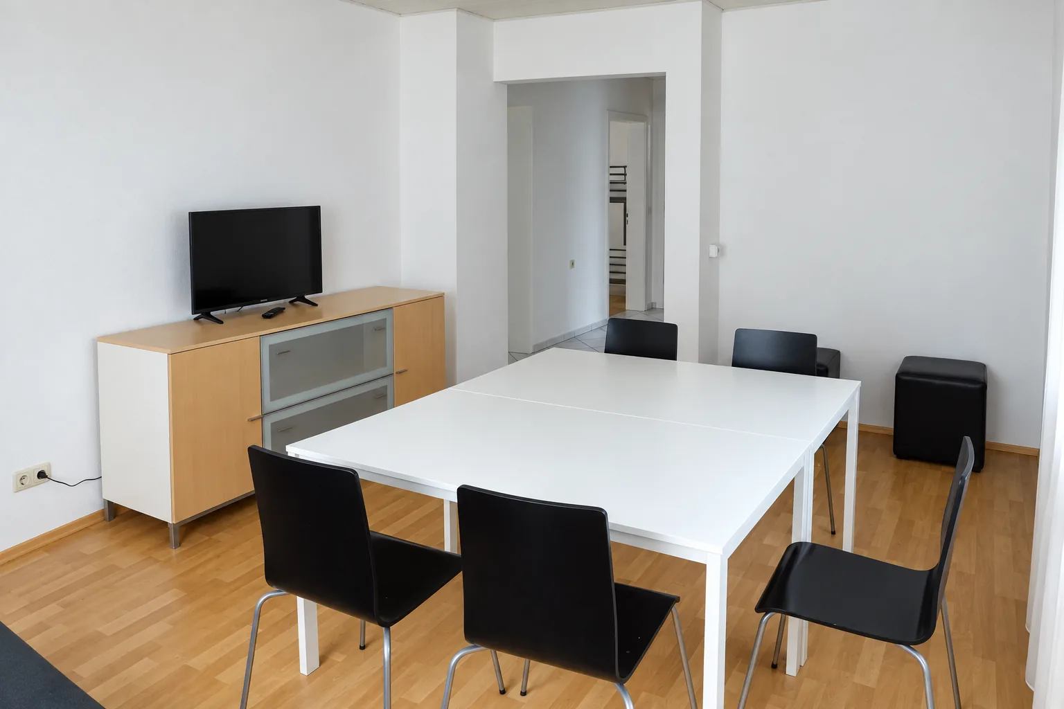 Gemeinschaftlicher Essbereich mit großem Tisch und TV in einer Monteurunterkunft in Augsburg