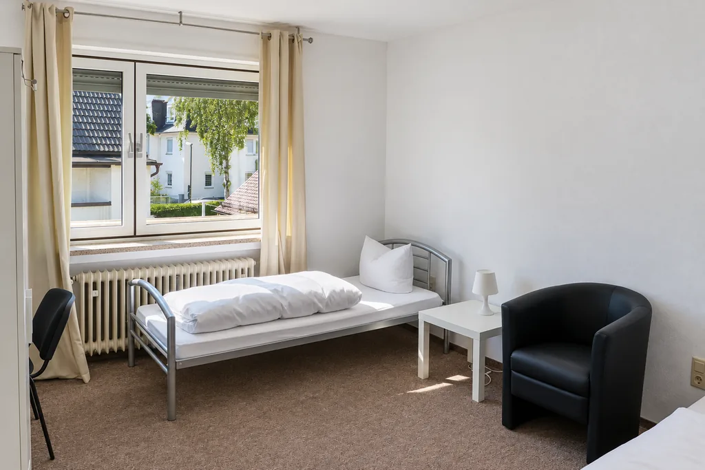 Apartment mit Bett, Sessel und Beistelltisch am Fenster