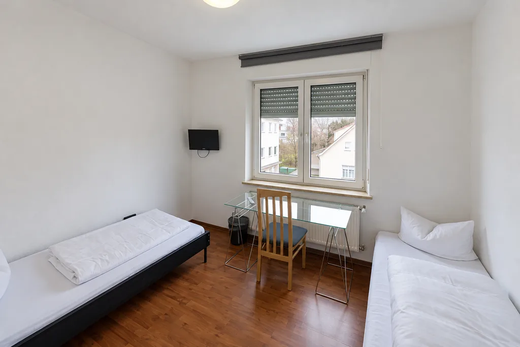 Helles Zimmer mit zwei Betten, Tisch und Stühlen in einer Monteurunterkunft in der Stiermannstraße